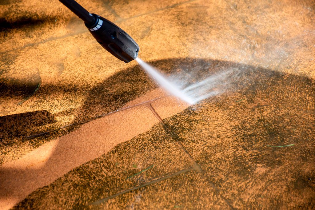 Cleaning backyard paving tiles with pressure washer